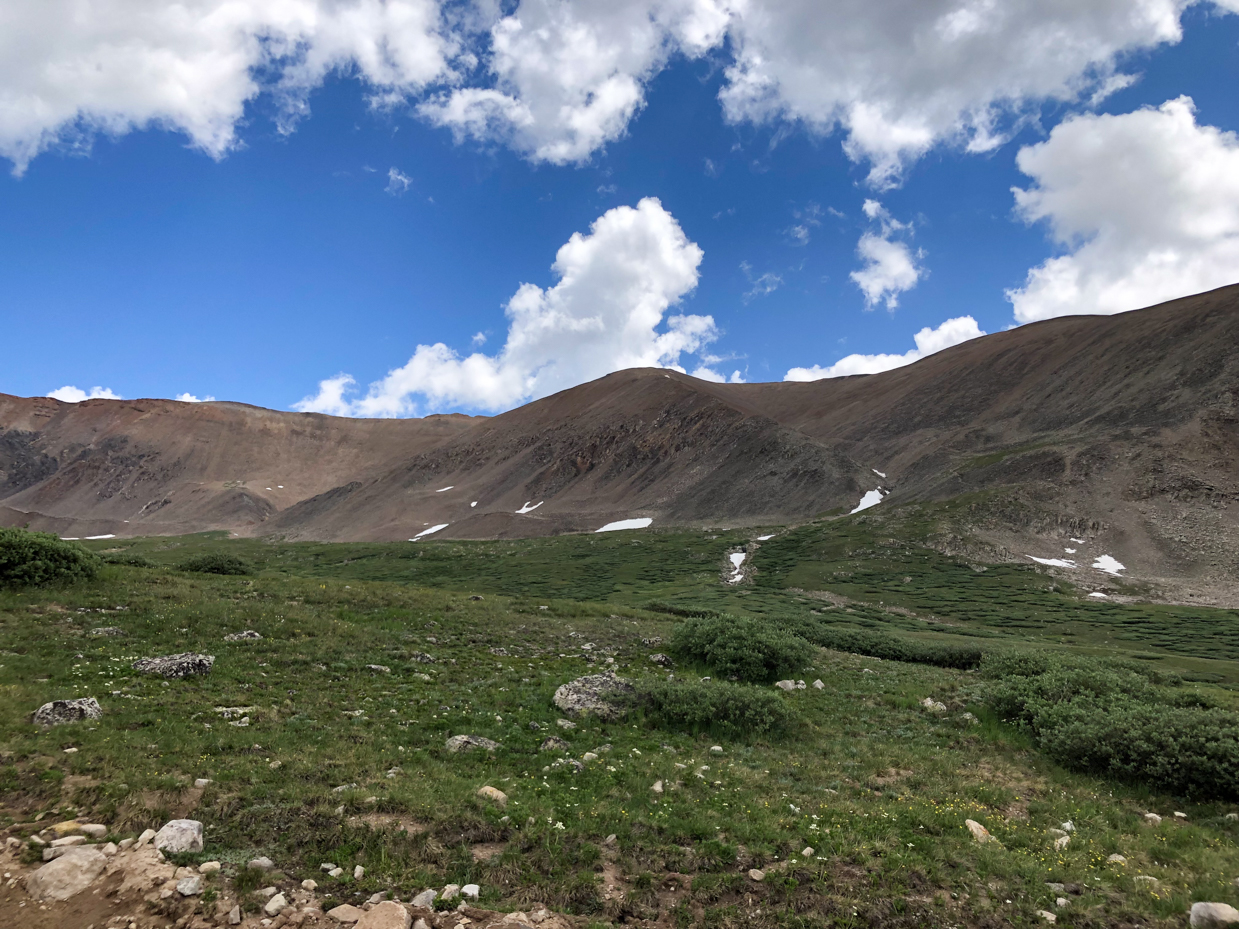 alpine-meadow-and-rugged-mountain-peaks-under-blue-sky