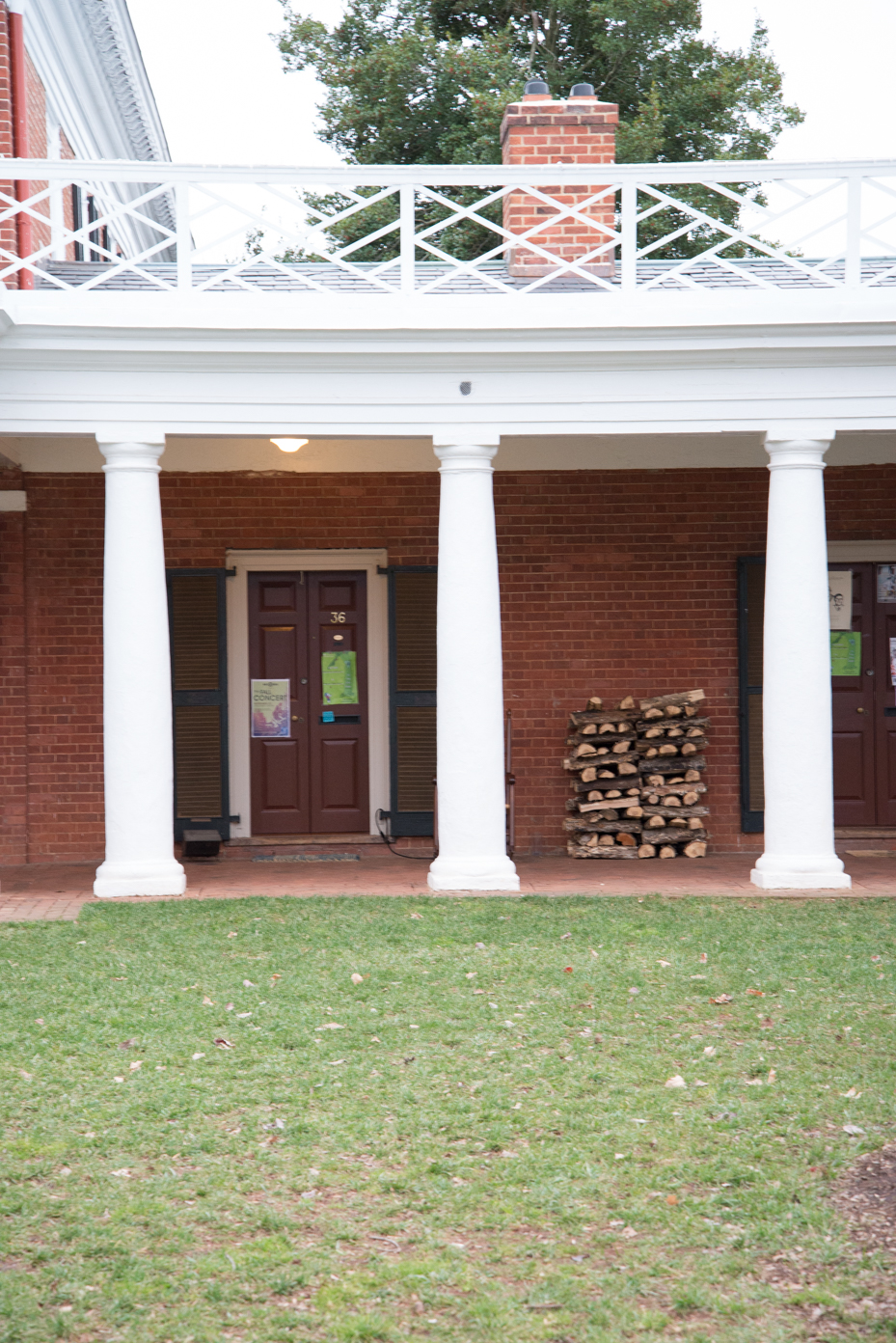 colonial-dormitory-entrance-brick-building-with-white-columns-decorative-railings-and-firewood-storage