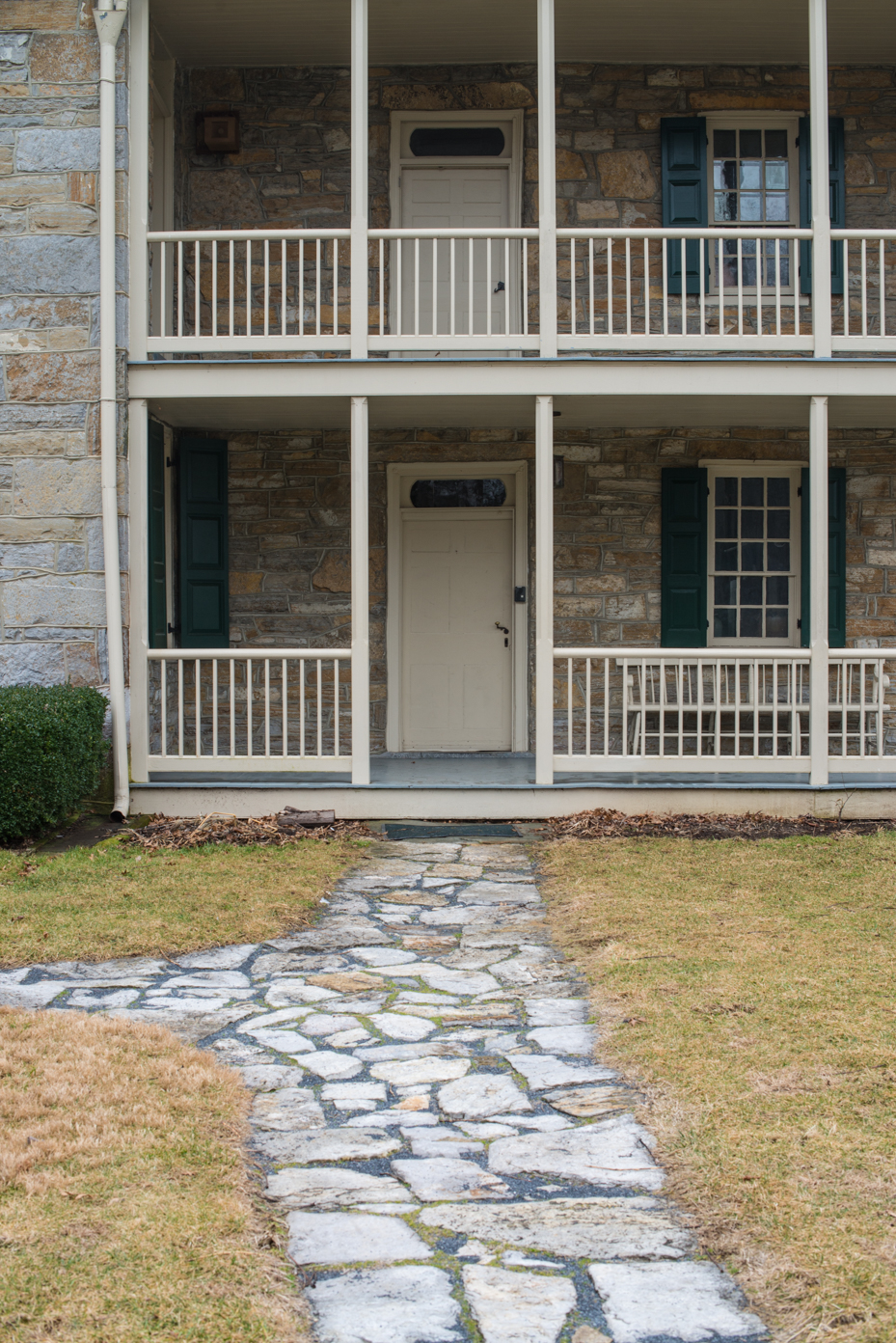 colonial-stone-house-entrance-double-decker-porch-with-flagstone-path-and-white-railings