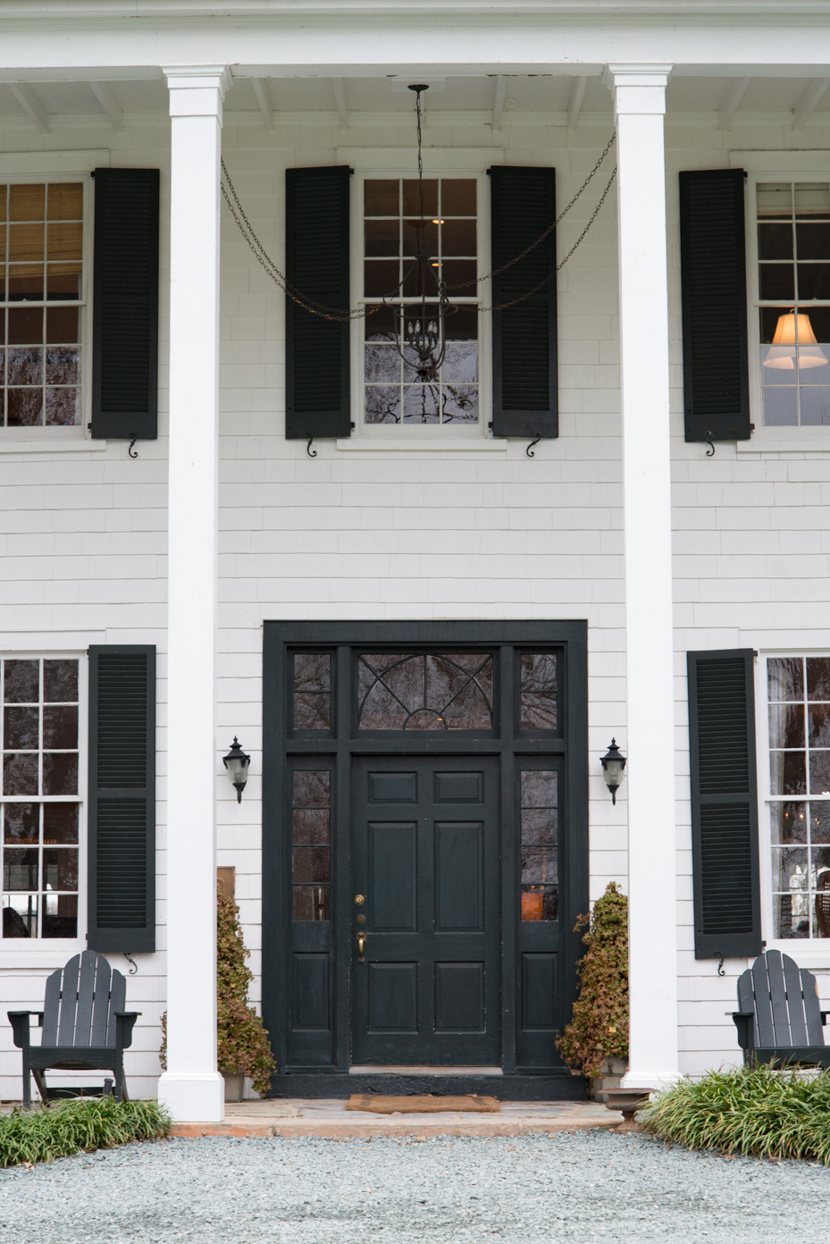 historic-colonial-house-entrance-with-forest-green-door-white-columns-and-adirondack-chairs-classic-new-england-architecture