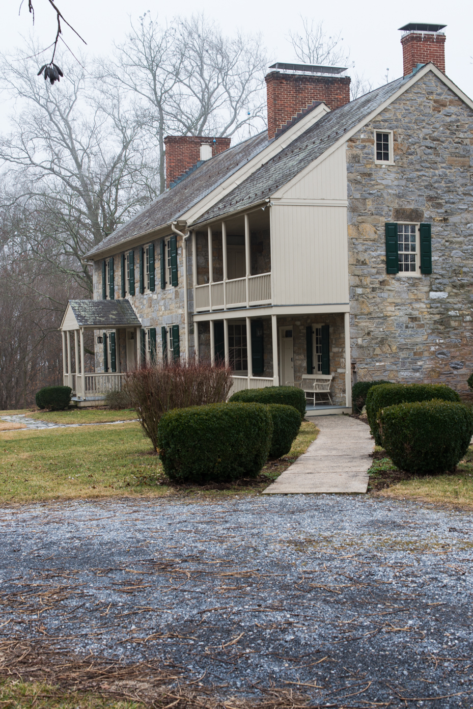 historic-stone-colonial-with-twin-porches-traditional-architecture-featuring-local-fieldstone-green-shutters-and-brick-chimneys