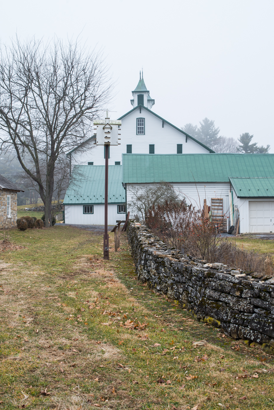 historic-white-barn-with-green-cupola-rural-architecture-with-stone-wall-and-metal-roof