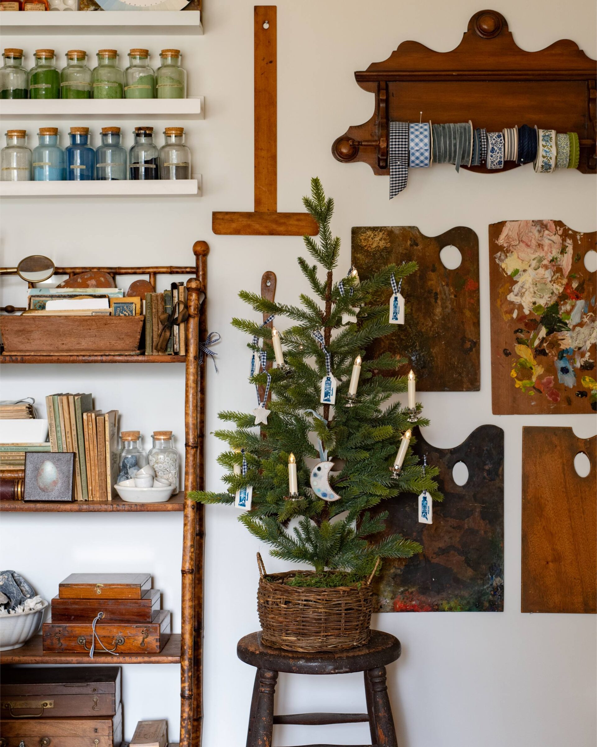 vintage-inspired-mini-christmas-tree-with-candles-and-star-ornaments-in-a-cozy-home-studio-decorated-with-art-supplies