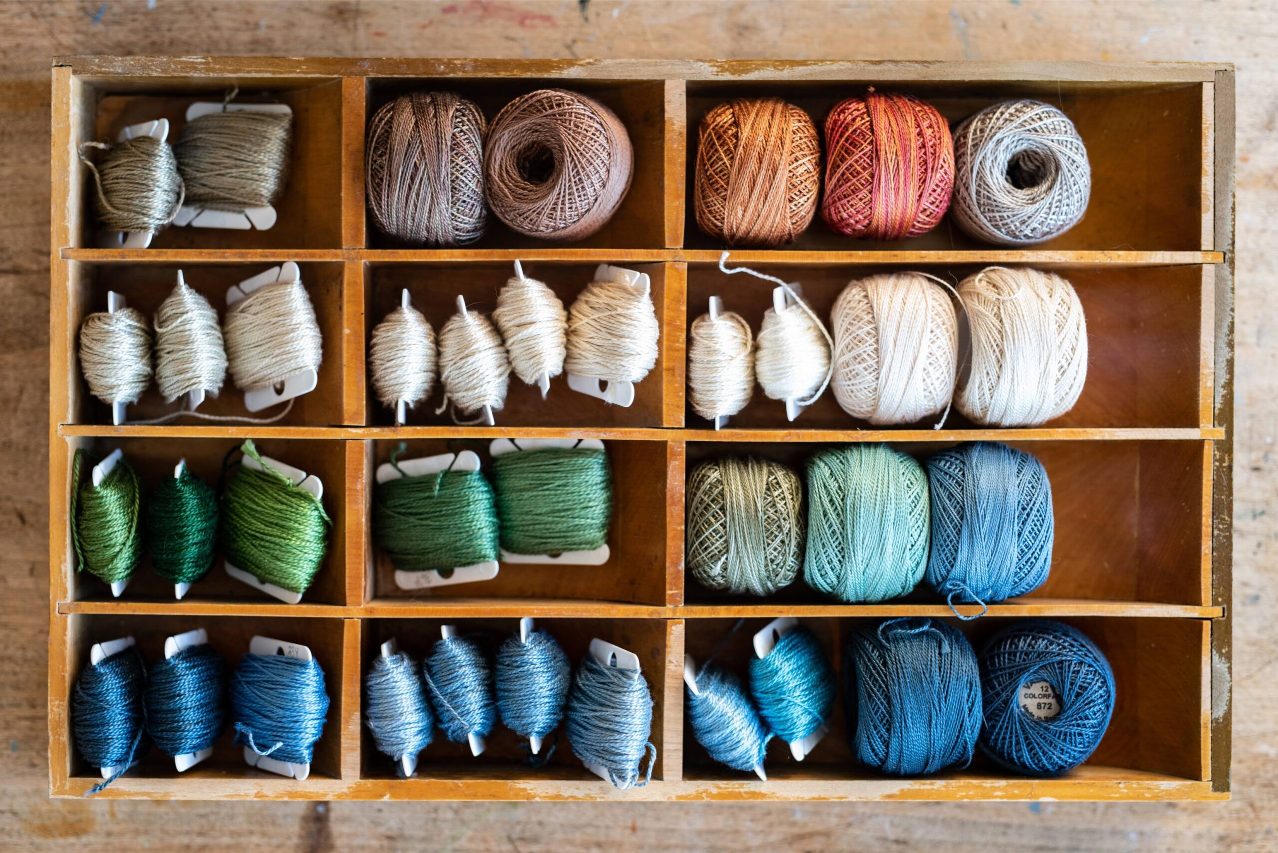 Vintage Wooden Thread Organizer with Assorted Yarn in Earthy Tones and Blues, Perfect for Crafting and Sewing Enthusiasts artist reference photo