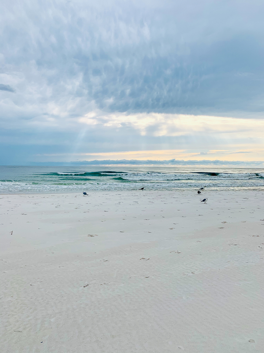 bright-sandy-beach-with-sunbeams-through-clouds-and-gentle-ocean-waves-serene-coastal-view