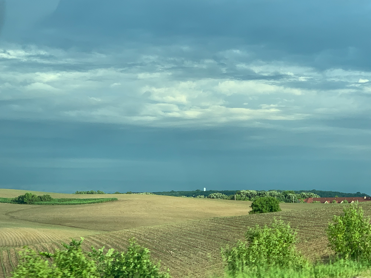 expansive-farmland-with-rolling-hills-and-dramatic-cloudy-sky-peaceful-rural-view