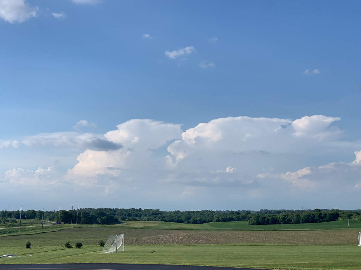 expansive-green-fields-with-cumulus-clouds-and-clear-blue-sky-tranquil-rural-landscape