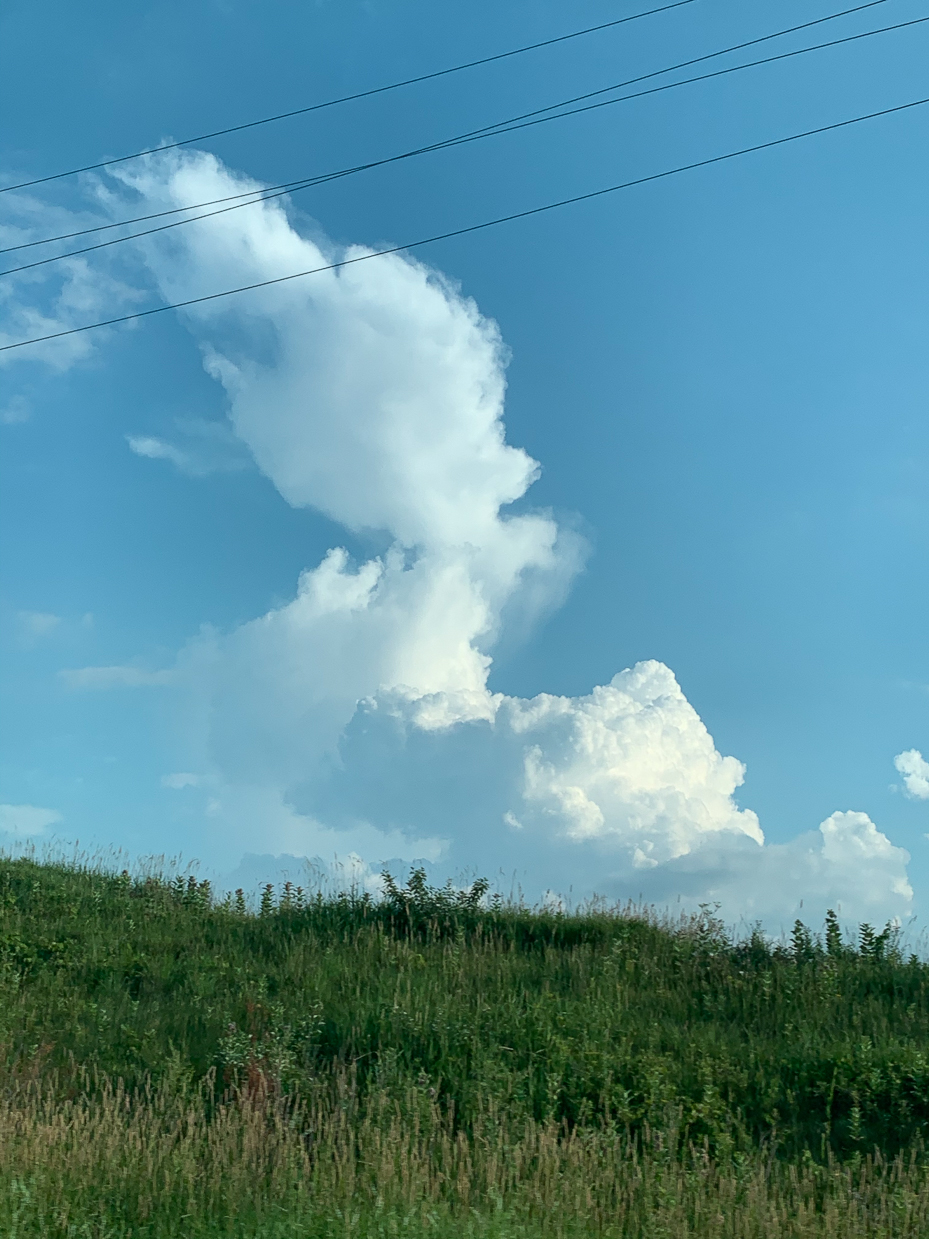 grassy-hillside-with-dramatic-cloud-formations-and-blue-sky-natures-serenity