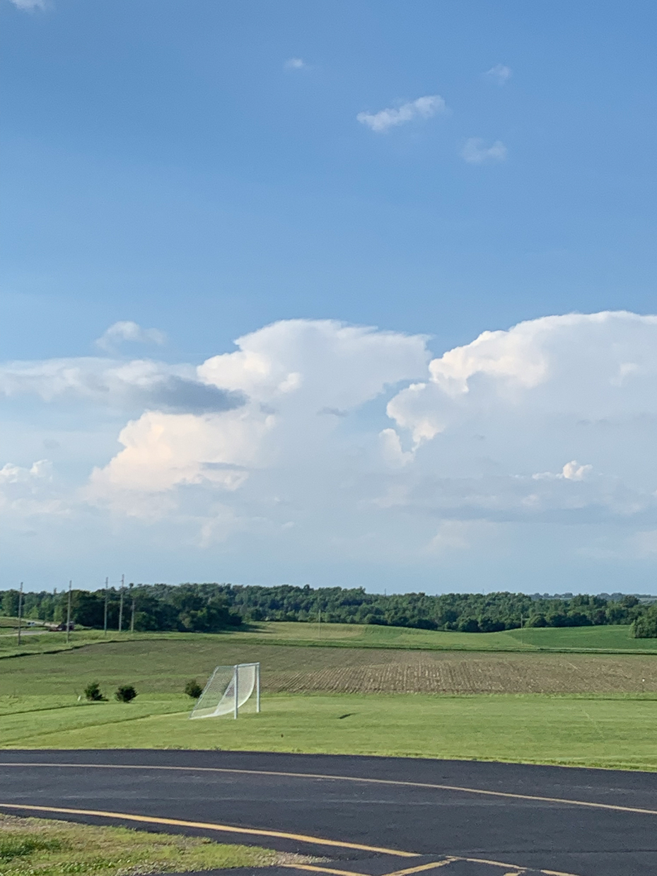 open-green-fields-with-puffy-clouds-and-bright-blue-sky-peaceful-countryside-setting