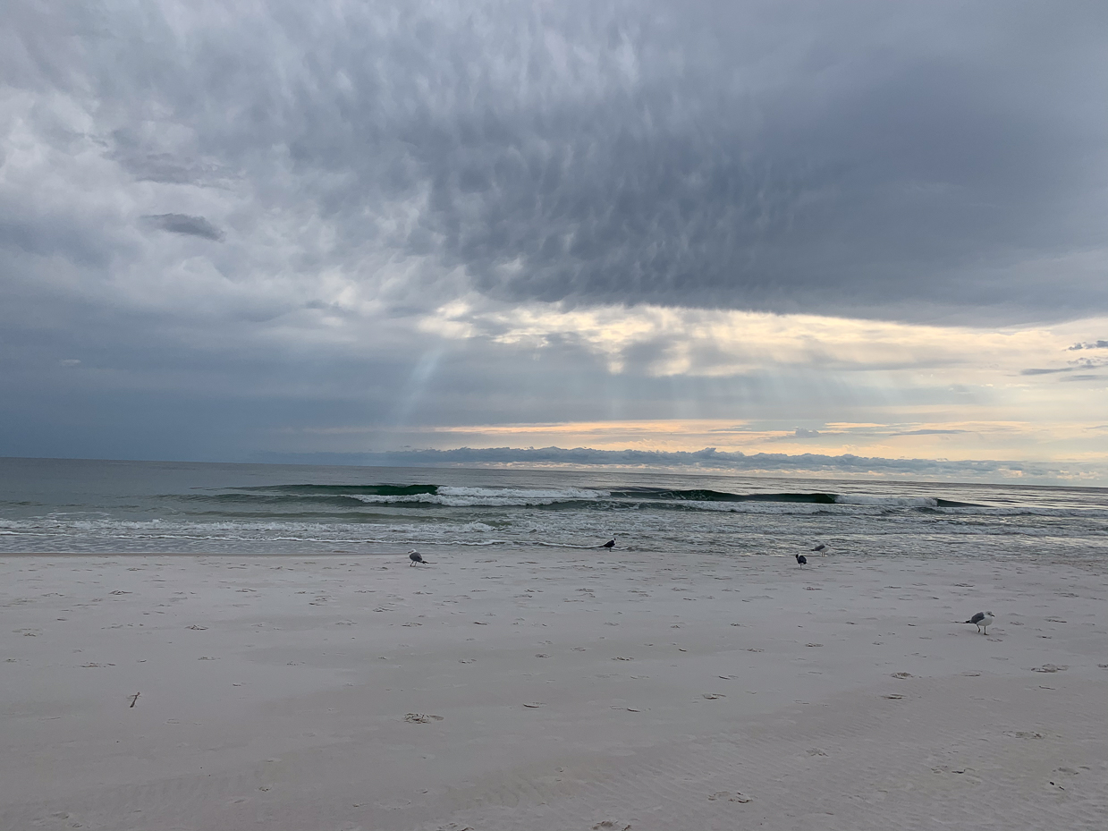 overcast-beach-with-sun-rays-breaking-through-clouds-and-gentle-waves-tranquil-coastal-scene