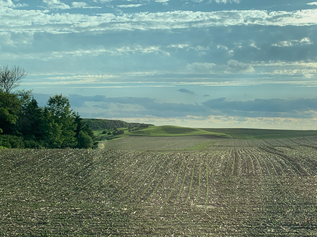 plowed-farmland-with-rolling-hills-and-a-layered-cloudy-sky-peaceful-rural-view