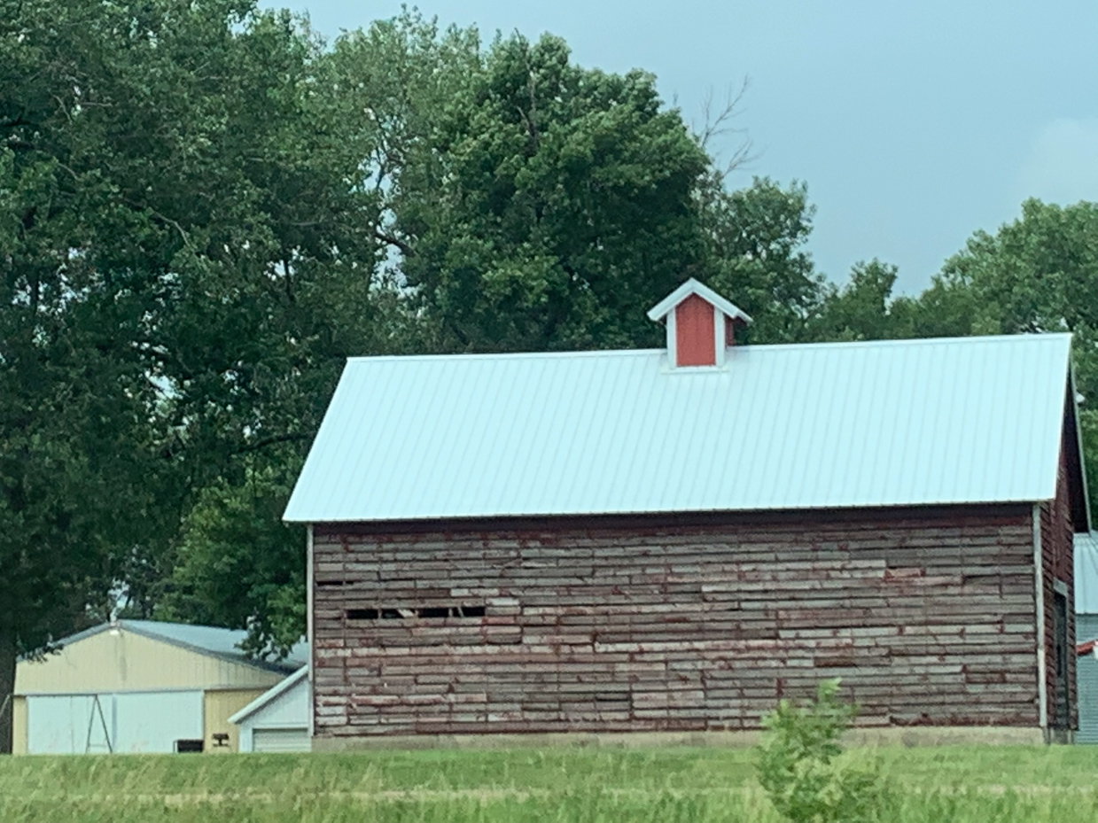 rustic-red-barn-with-white-roof-surrounded-by-trees-idyllic-countryside-view