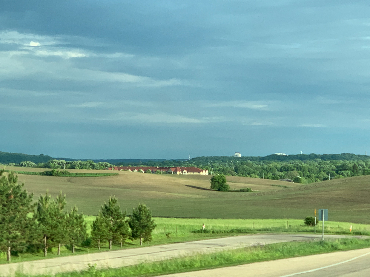 scenic-farmland-with-rolling-hills-distant-buildings-and-a-dramatic-sky-countryside-landscape