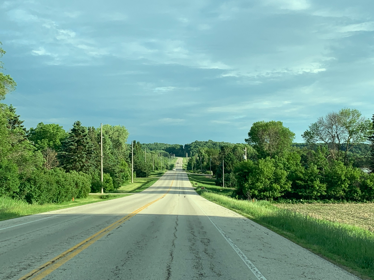 straight-country-road-surrounded-by-lush-greenery-under-a-cloudy-sky-peaceful-drive