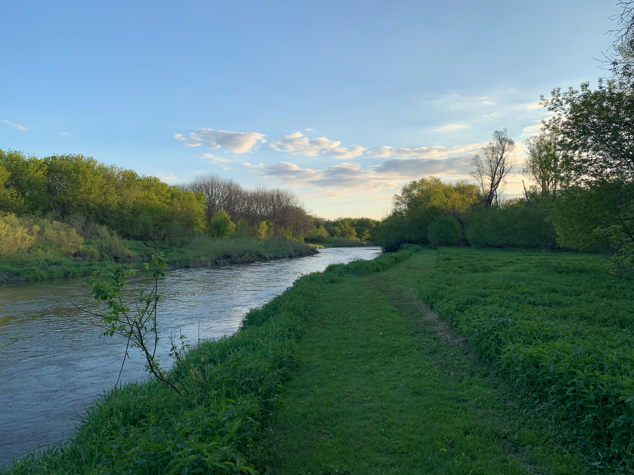 tranquil-river-scene-with-green-riverbank-and-soft-evening-sky-nature-at-dusk