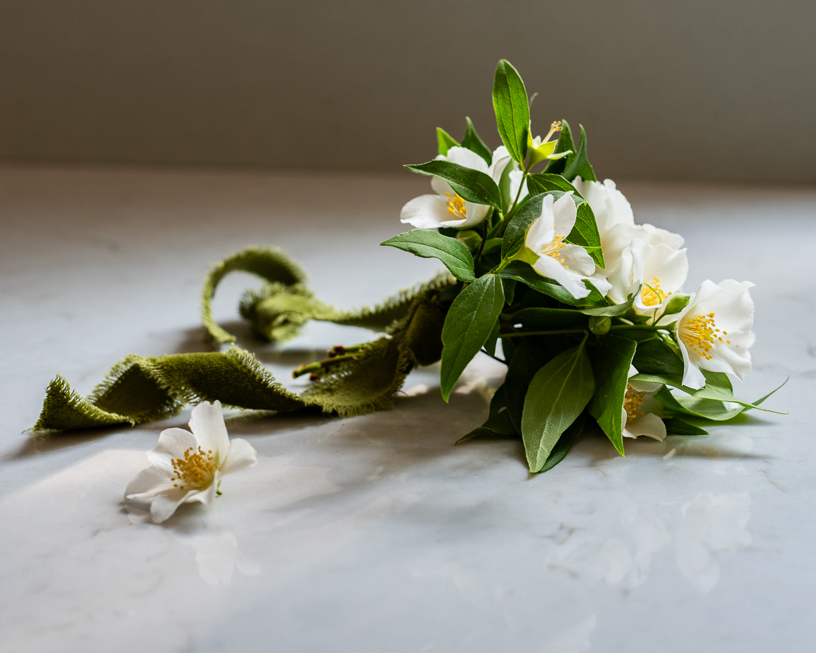 close-up-of-mock-orange-flower-bouquet-and-velvet-ribbon-on-marble-counter-artist-reference-photo