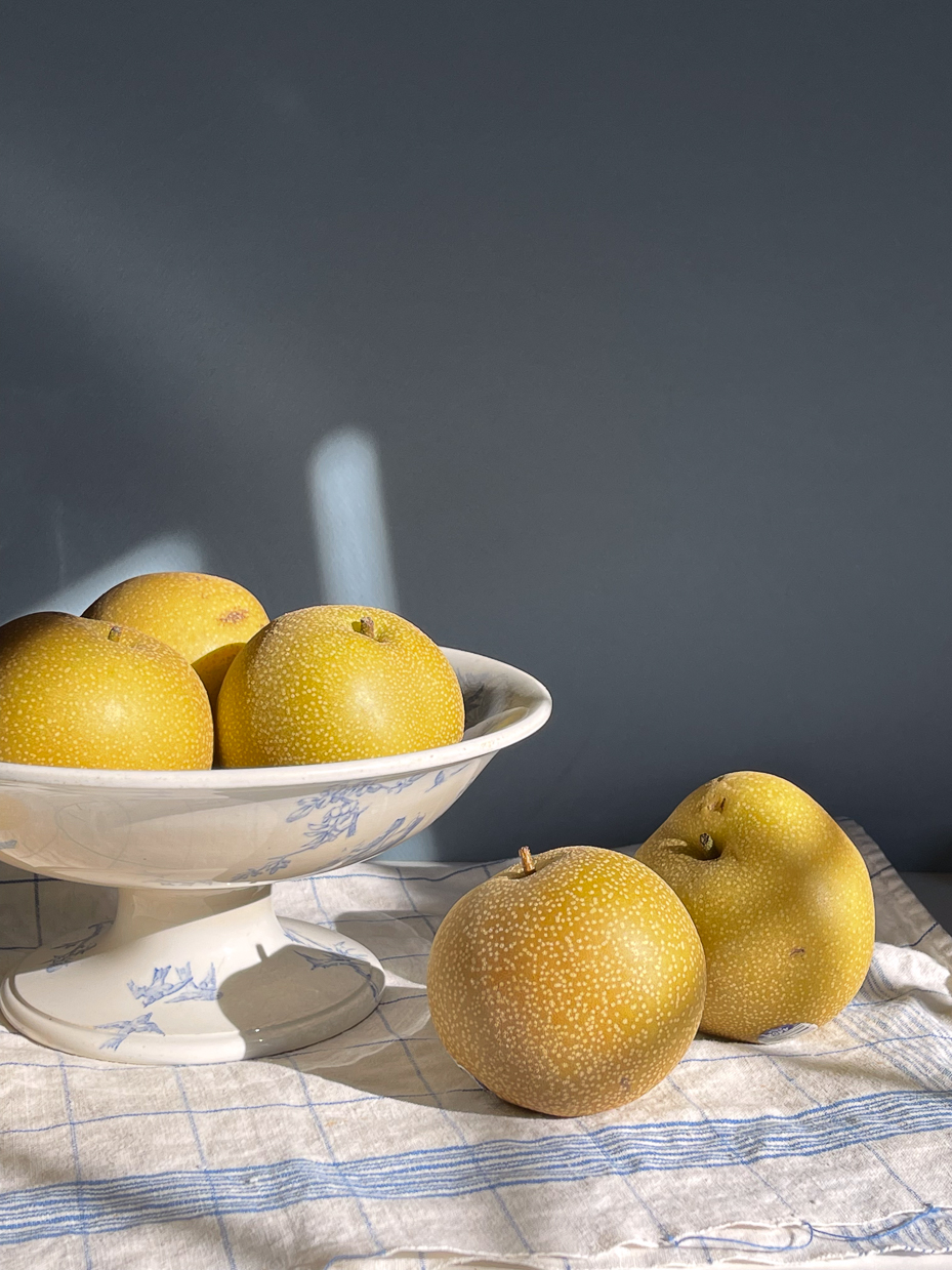 golden-asian-pears-in-antique-blue-and-white-pedestal-bowl-with-sunlight