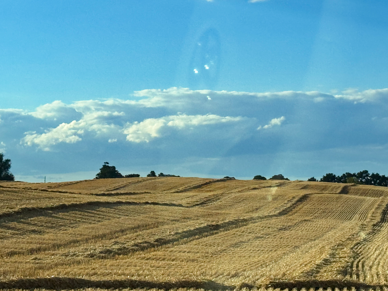 harvested-field-with-rolling-hills-and-dramatic-cloudy-sky-rural-landscape-photography