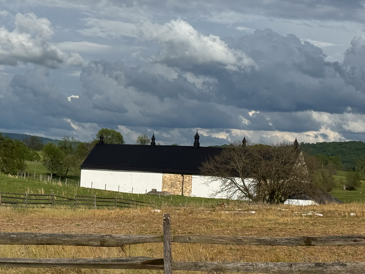 historic-black-roofed-barn-with-stone-and-white-siding-beneath-stormy-skies-artist-reference-photo