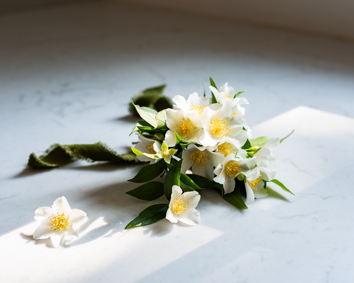 mock-orange-flower-bouquet-with-velvet-ribbon-and-scattered-blooms-on-sunlit-marble-surface-artist-reference-photo