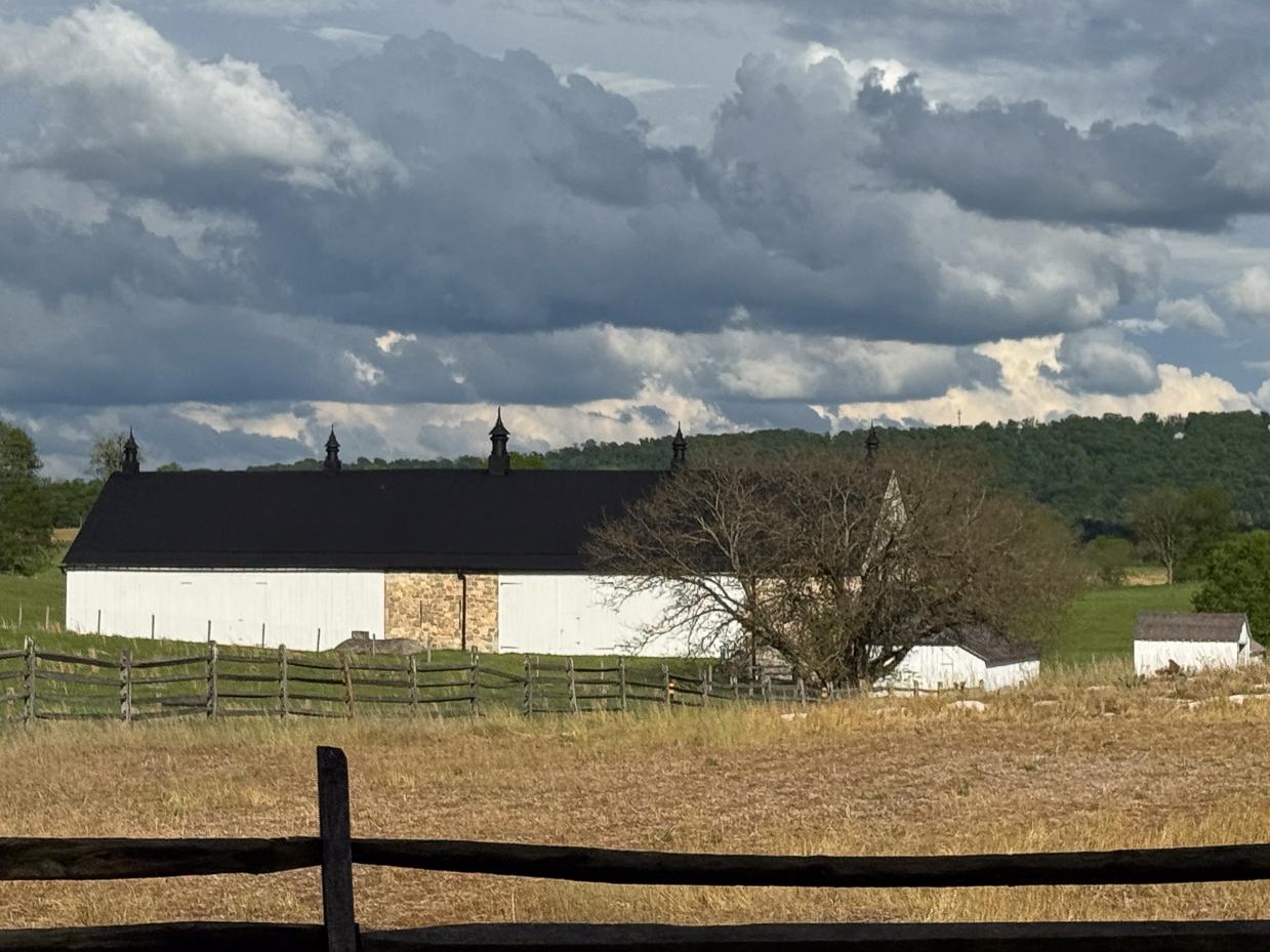 white-barn-with-black-cupolas-and-stone-accent-under-moody-sky-artist-reference-photo