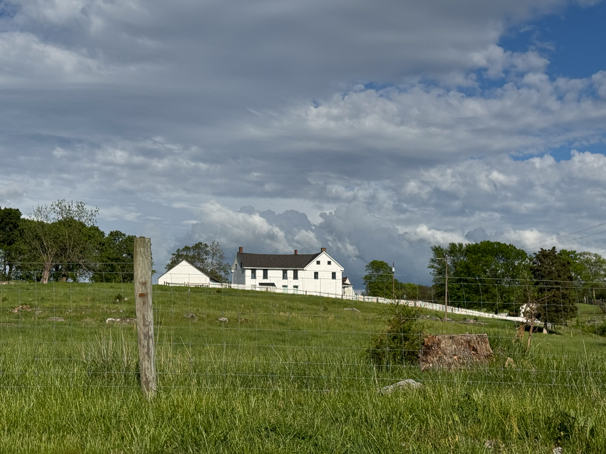 white-farmhouse-on-grassy-hill-with-stormy-sky-and-fence-post-artist-reference-photo