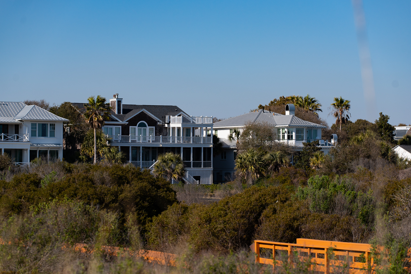 row-of-luxury-beachfront-homes-with-palm-trees-and-boardwalk