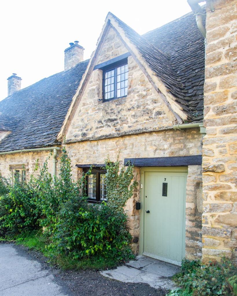 Close view of gabled stone cottage with green door and ivy artist reference photo