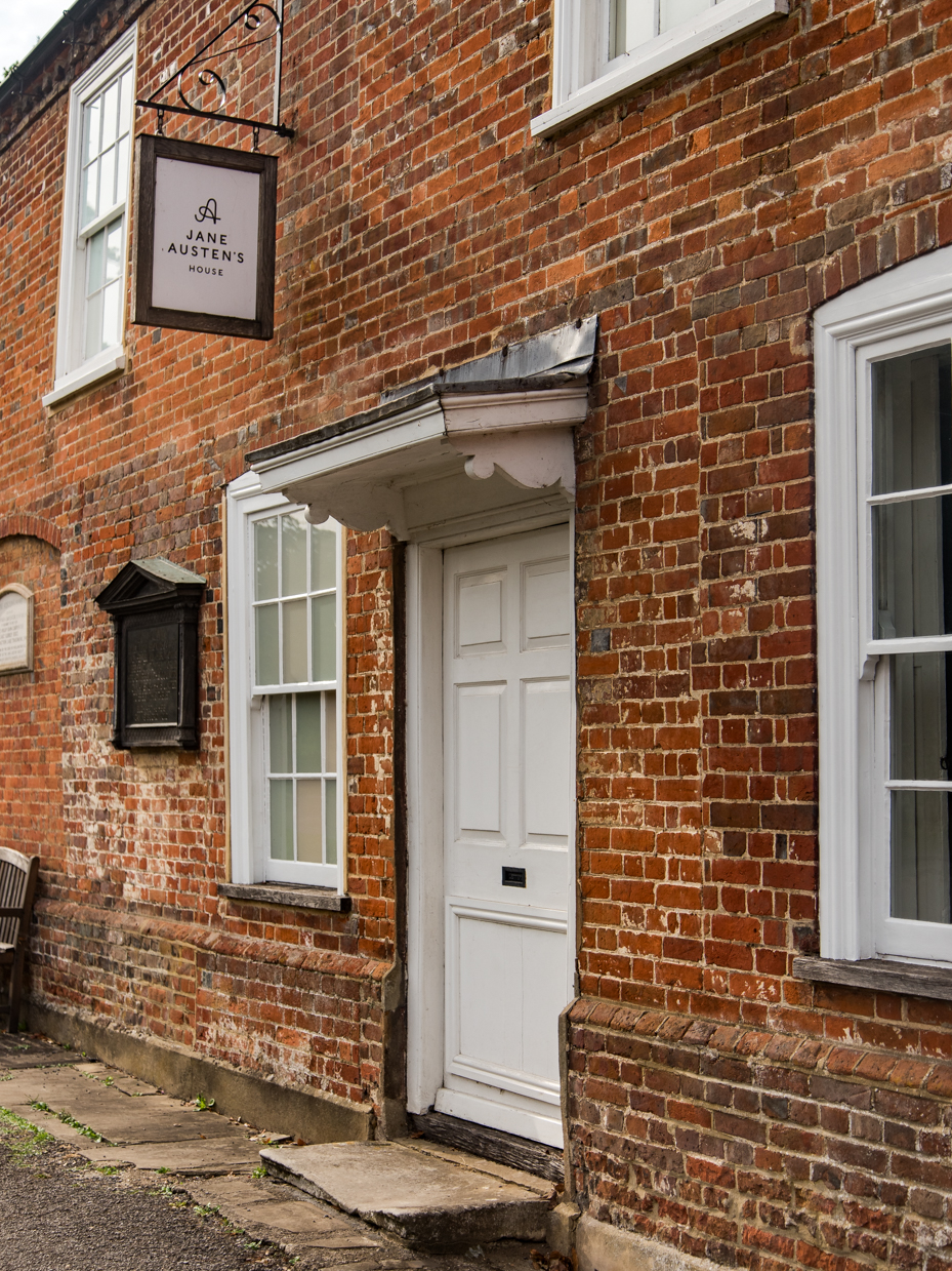 Historic Brick Building Exterior with White Door and Hanging Sign artist reference photo