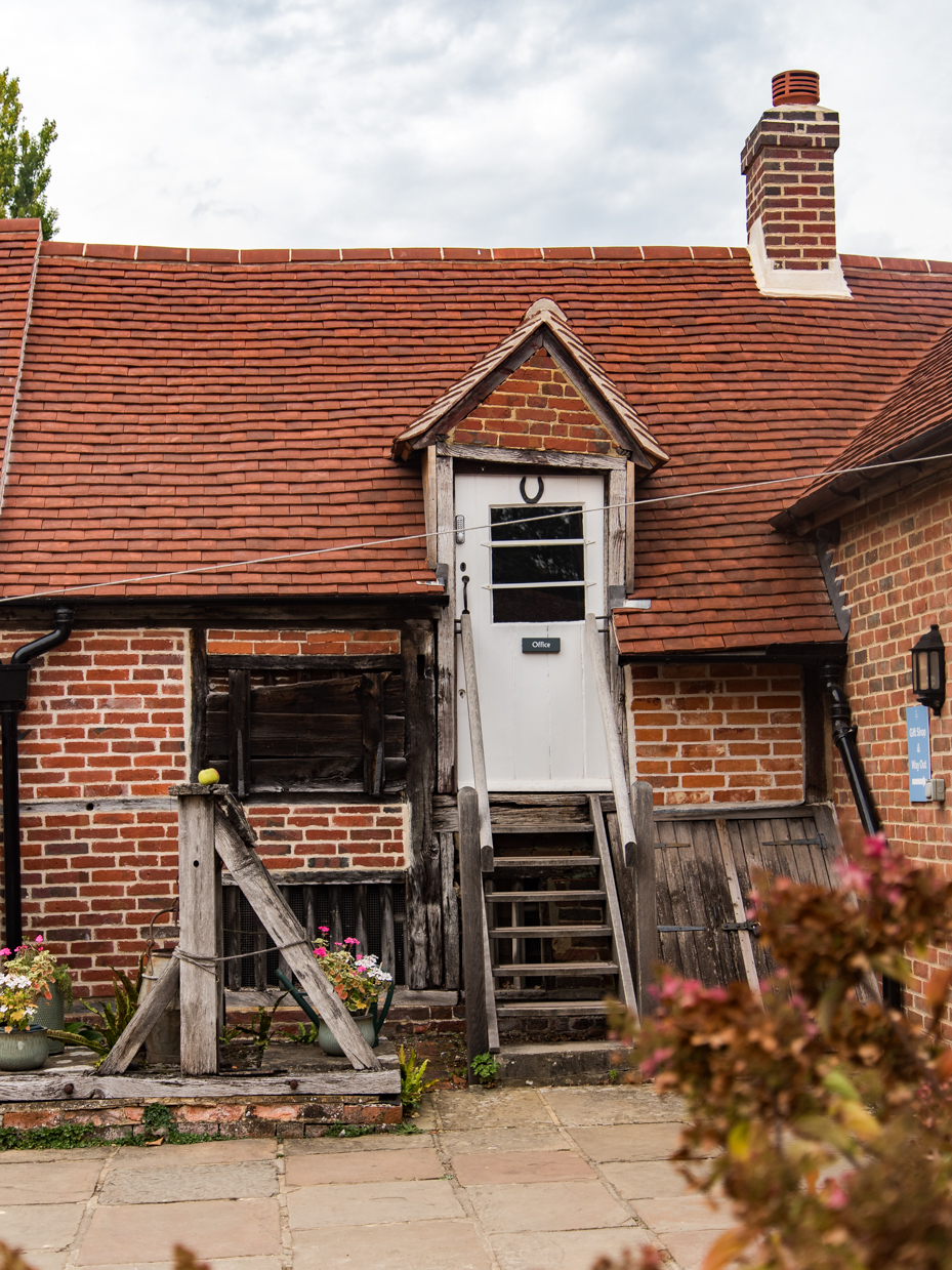 Rustic Brick Outbuilding with Wooden Stairs and Red Tile Roof artist reference photo