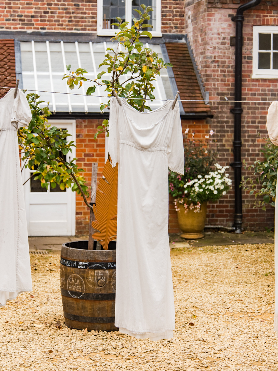 White Linen Dress Hanging in Courtyard with Brick House Background artist reference photo